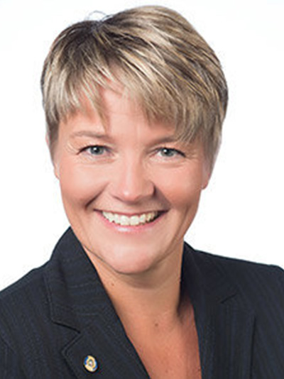 Susanne Holmberg smiling with white background and a dark blazer on